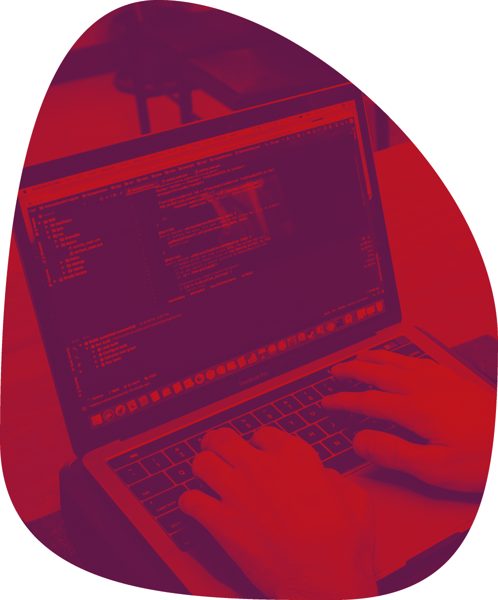 A person typing on a laptop with a code editor open, displaying lines of code. The image has a red overlay and a rounded triangular shape.